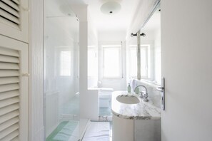 A bathroom with a sink, mirror, and shower.