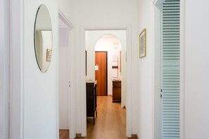 A hallway with a mirror, a door, and a light blue shutter.