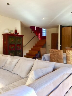Relax in this stylish living room with a sofa, wicker chair, and staircase leading to an upper level.