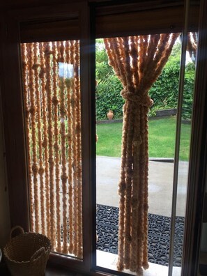 A door with a unique curtain design frames the view of a well-maintained garden.