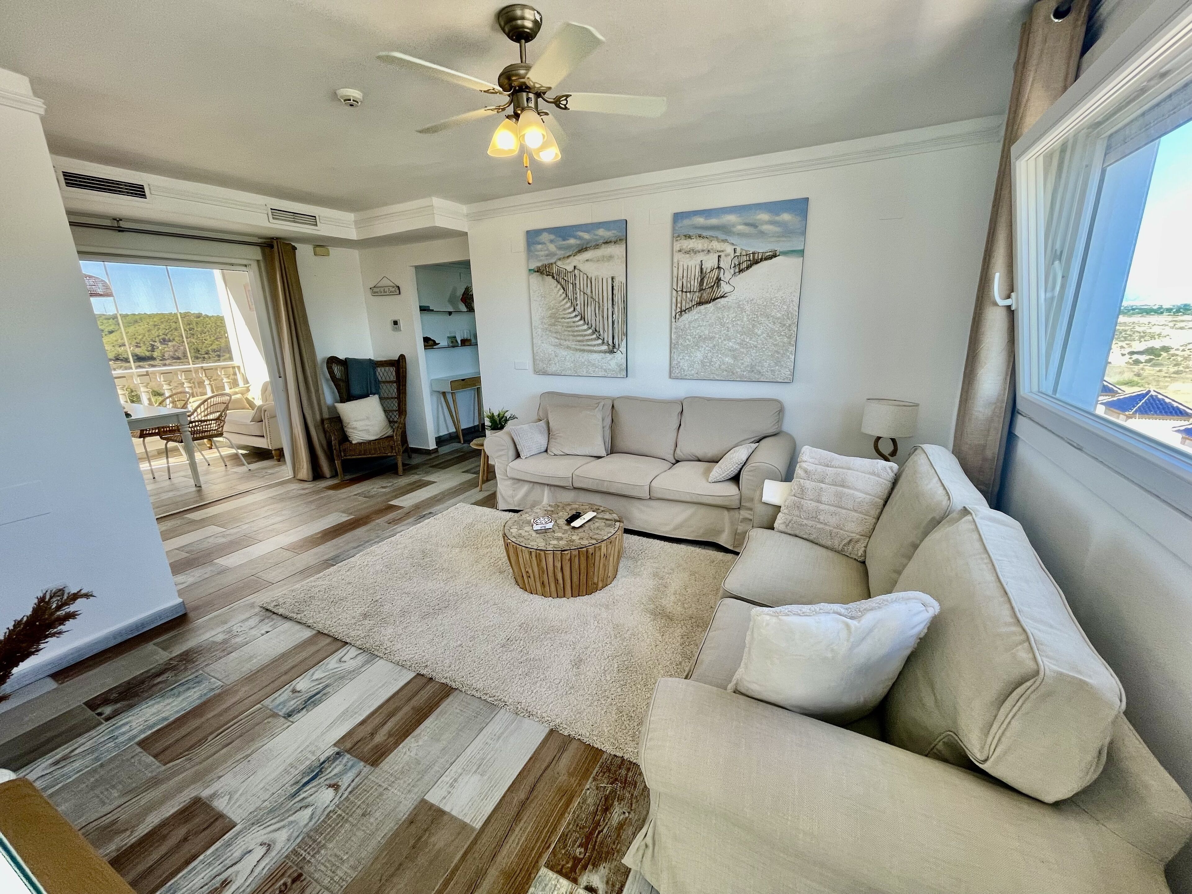 A spacious living room with a beige sofa, a round coffee table, and a ceiling fan.