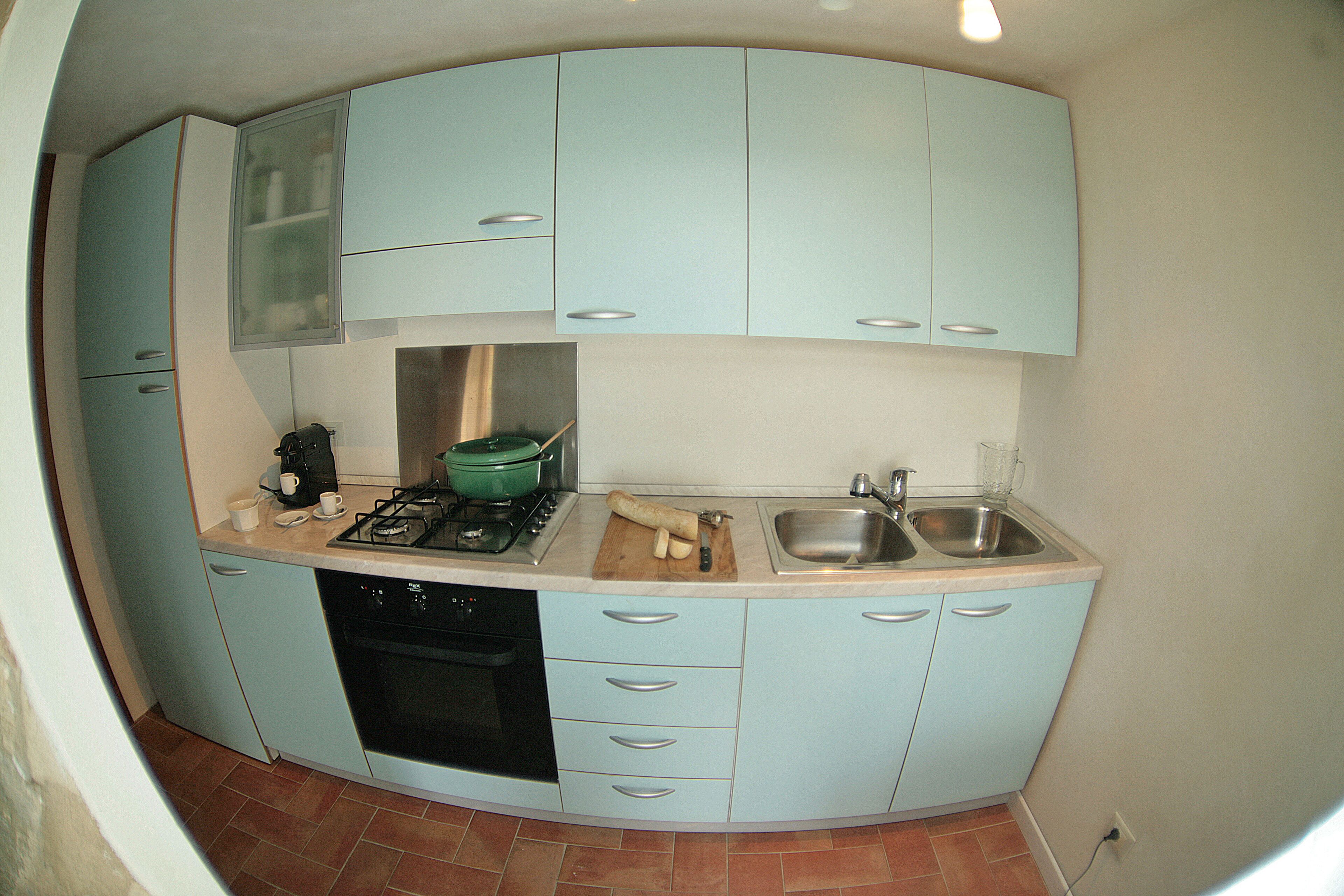 A compact kitchen with light blue cabinets, a stove, a sink, and a dishwasher.