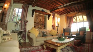 Una sala de estar acogedora con un sofá, sillones, una mesa de centro y una alfombra estampada.
