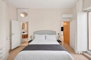 Ein modernes Schlafzimmer mit Bett, Nachttischen, einem Kleiderschrank und einer Klimaanlage.