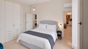 Un dormitorio con cama, armario y baño visible a través de una puerta abierta.
