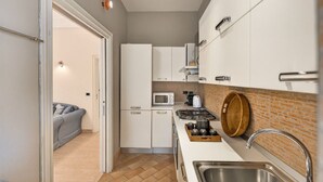 Una cocina compacta con armarios blancos, un microondas, una estufa y un lavamanos.