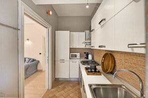 A compact kitchen with white cabinets, a microwave, a stove, and a sink.