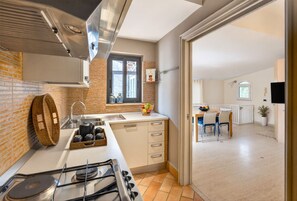 Une cuisine équipée d’une cuisinière à gaz, d’un évier et d’une fenêtre. On y trouve également un coin repas avec une table et des chaises.