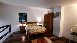 Ein Schlafzimmer mit einem hölzernen Bett, Nachttischen, einem Kleiderschrank und einem Bild an der Wand.