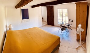 A room with a bed, a table with chairs, a fan, and a window. - Authentic magnanerie (Fayence)