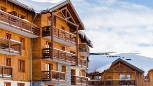 Una cabaña de madera de varios pisos con balcones, con una imponente montaña nevada al fondo.