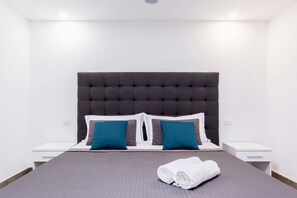 A neatly made bed with a grey headboard, two blue pillows, and a white towel on the side. - Modern Sorrento Apartment with Terrace&TennisCourt (Sorrento)