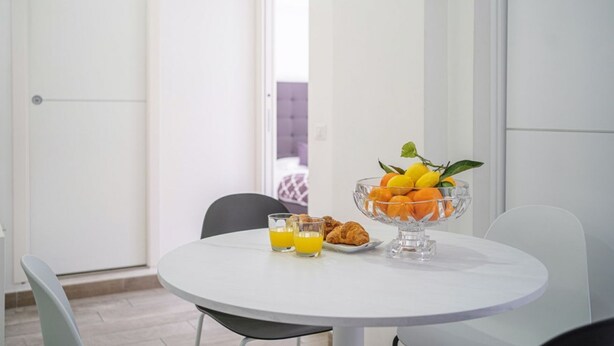 Ein Esstisch mit einer Obstschale, zwei Gläsern Orangensaft und Croissants.
