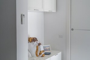 A room with a white cabinet, a phone, a framed picture, and a decorative item on a desk.
