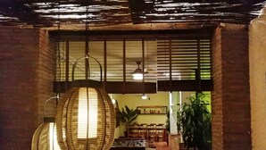 A cozy interior with a sofa, hanging wicker lamps, and a dining area with chairs and a table. - ALQUERIA DE GÍTAR. Beautiful rural villa for 20 people close to the sea (Felix)