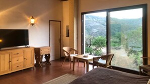 A room with a large TV, wooden furniture, a dining area, and a large window with a view of the countryside. - ALQUERIA DE GÍTAR. Beautiful rural villa for 20 people close to the sea (Felix)