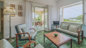 A room with a sofa, chairs, a TV, and a table. There is a balcony with a view of the sea. - A Country House by the Sea (Procchio)