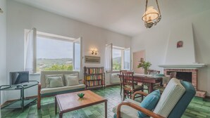 A cozy living room with a fireplace, a dining area, and a bookshelf. - A Country House by the Sea (Procchio)