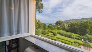 A room with a view of a lush garden and distant coastline. - A Country House by the Sea (Procchio)