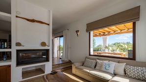 Un salon moderne comprenant un canapé, une table basse en bois, une cheminée et une grande fenêtre donnant sur l’extérieur.