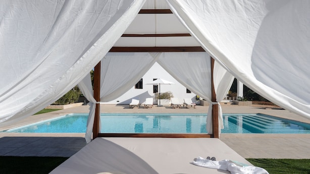 Un espace de détente aménagé au bord de la piscine, avec des parasols blancs, une piscine et des chaises longues.