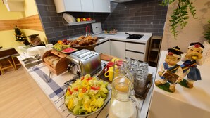 A kitchen with a buffet setup including a salad, bread, and a toaster. - DAOL guest house (Seoul)