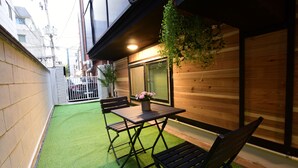 A small outdoor patio with a table and chairs, a hanging plant, and a view of the street. - DAOL guest house (Seoul)