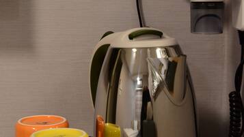 A coffee maker, two mugs, and a telephone on a wooden surface.