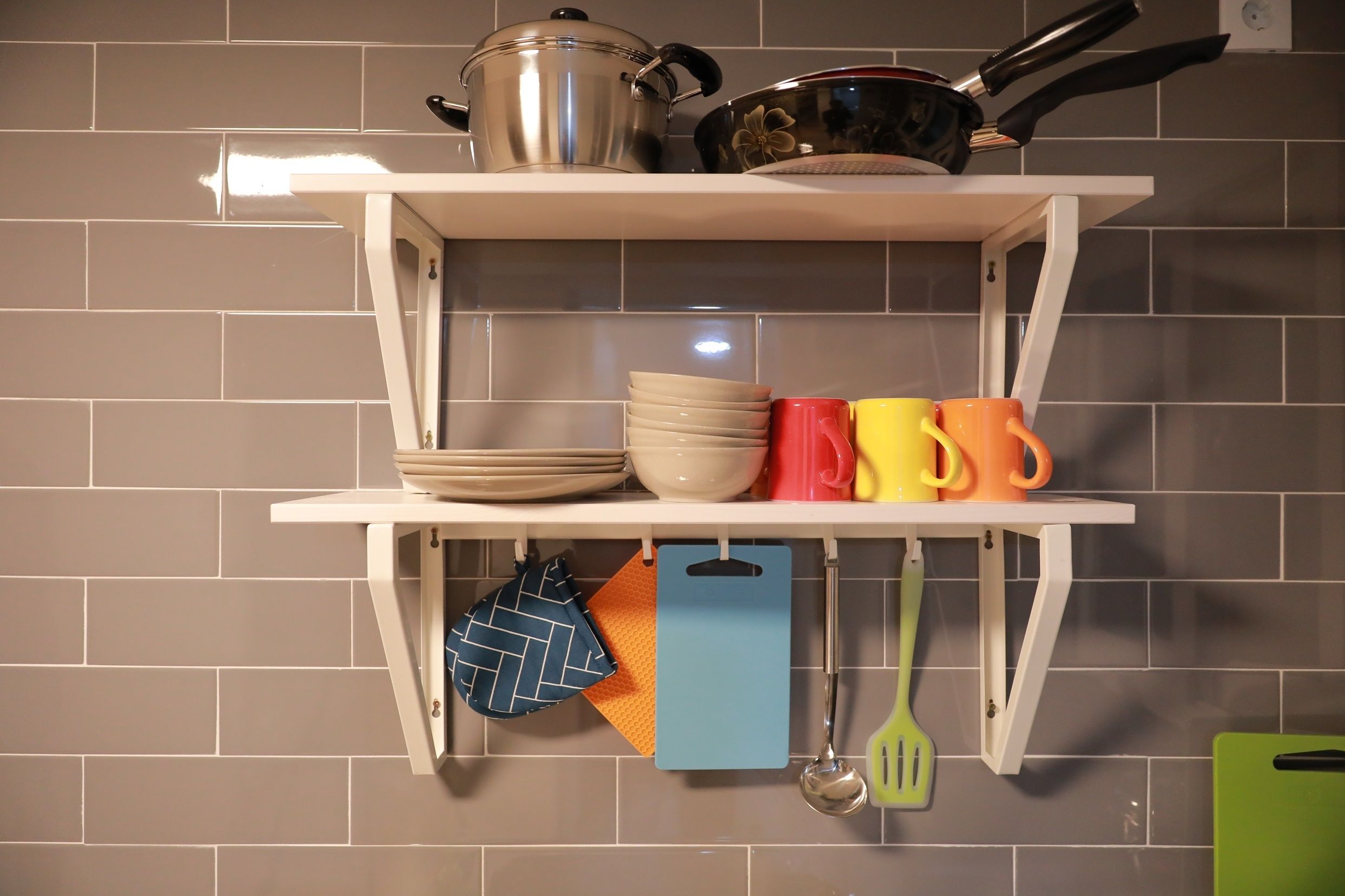 A kitchen shelf with cookware, plates, and utensils.