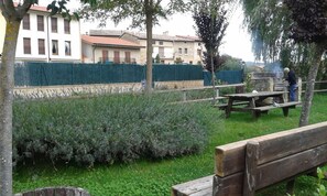 Un parque con un banco de madera, una mesa de picnic y una parrilla de piedra.