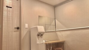 A bathroom with a shower, a water dispenser, a mirror, and a stool. - Dawoo House - Hostel (Seoul)