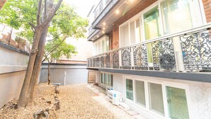 A building with a balcony, a tree, and a gravel area. - Dawoo House - Hostel (Seoul)