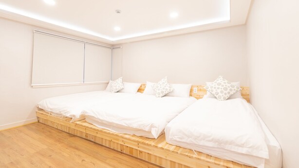A modern bedroom with two beds, wooden flooring, and a large window. - Dawoo House - Hostel (Seoul)