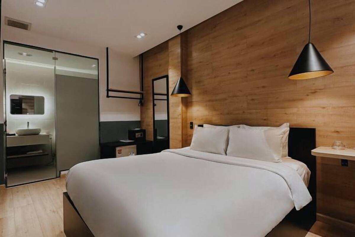 Une chambre à coucher moderne avec un grand lit, un lambris en bois, une table de chevet et une commode.