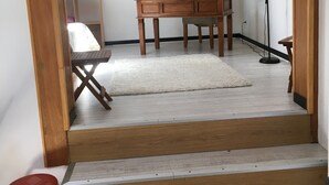 Un escalier menant à une pièce où se trouvent un bureau, une chaise et un téléviseur posé sur une étagère.