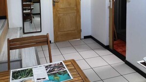 Une petite pièce avec une porte en bois, un miroir, une table avec un menu et un appareil de climatisation.