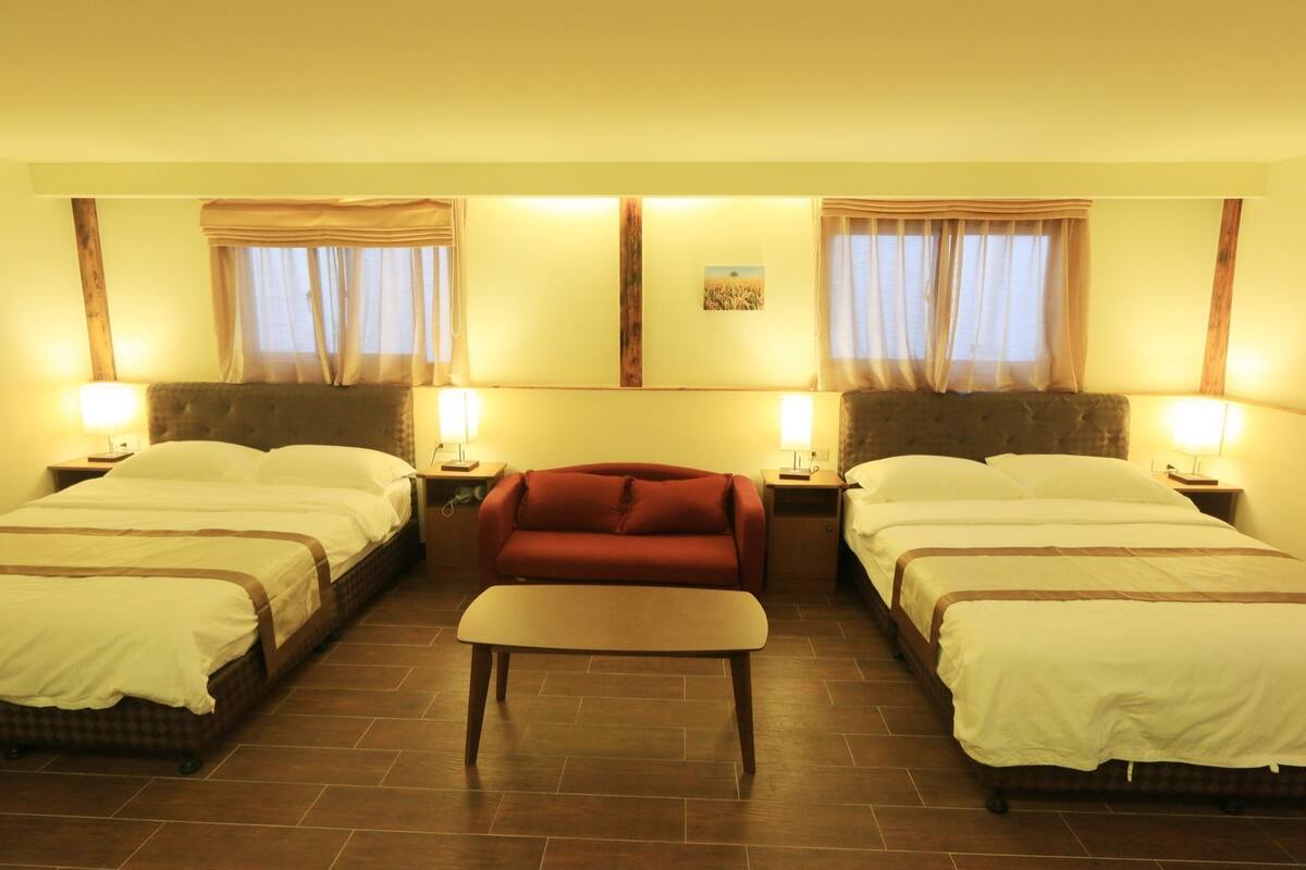 A hotel room with two beds, a sofa, and a small table.