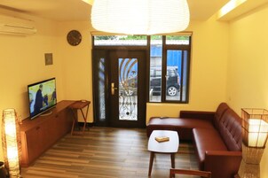 Una sala de estar con televisor, sofá y mesa.