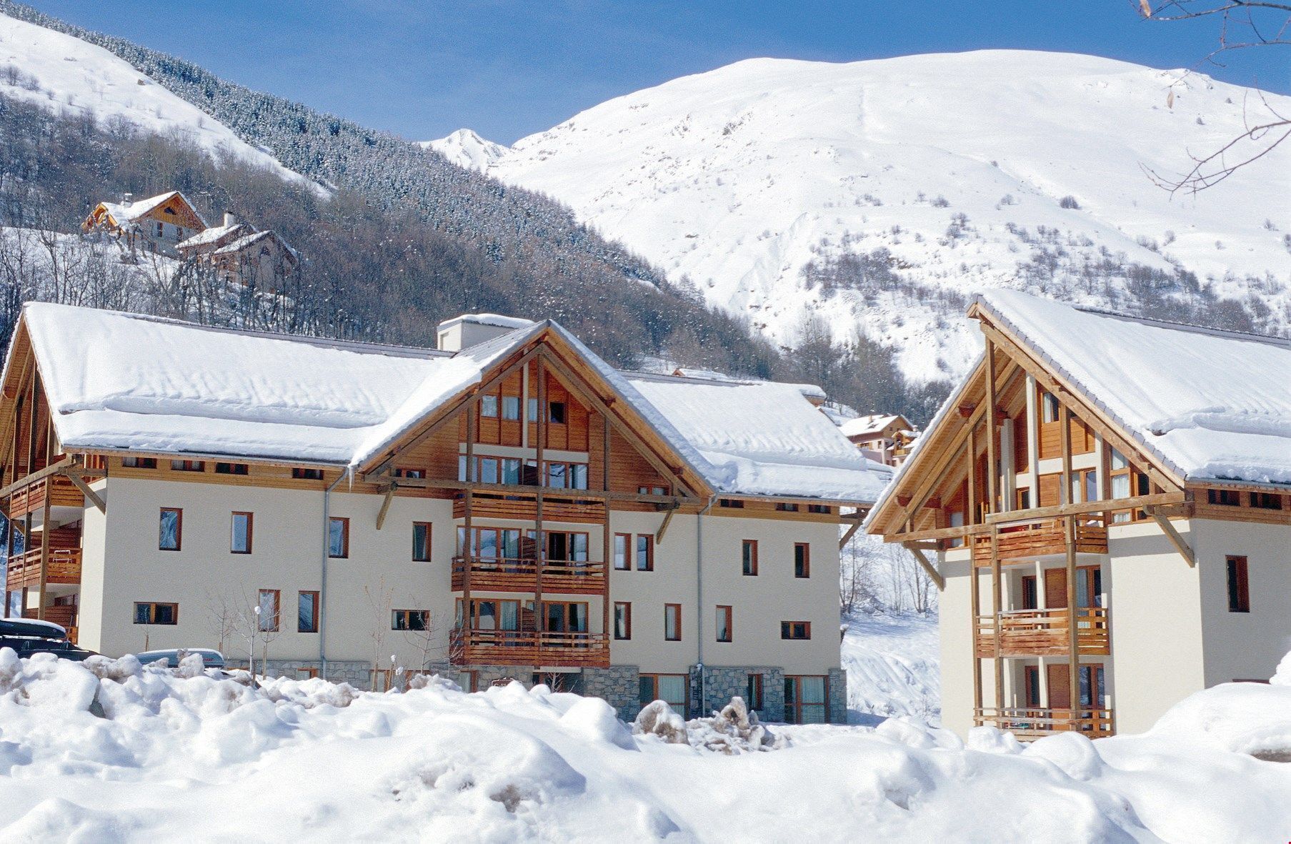 Ett hotell i chalet-stil med flera balkonger av trä och en bergig bakgrund.