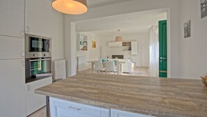 Una cocina moderna con armarios blancos, horno empotrado y encimera de madera.
