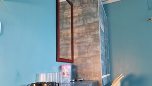 Una habitación con pared azul, una encimera de madera, un espejo y una silla.