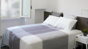 Une chambre à coucher moderne avec un lit, une table de chevet et une fenêtre.