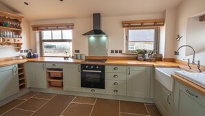 A spacious kitchen with a central island, built-in oven, and a large window providing natural light. - The Old Farmhouse - 2 Bedroom property, stunning character, views & location (Derbyshire)