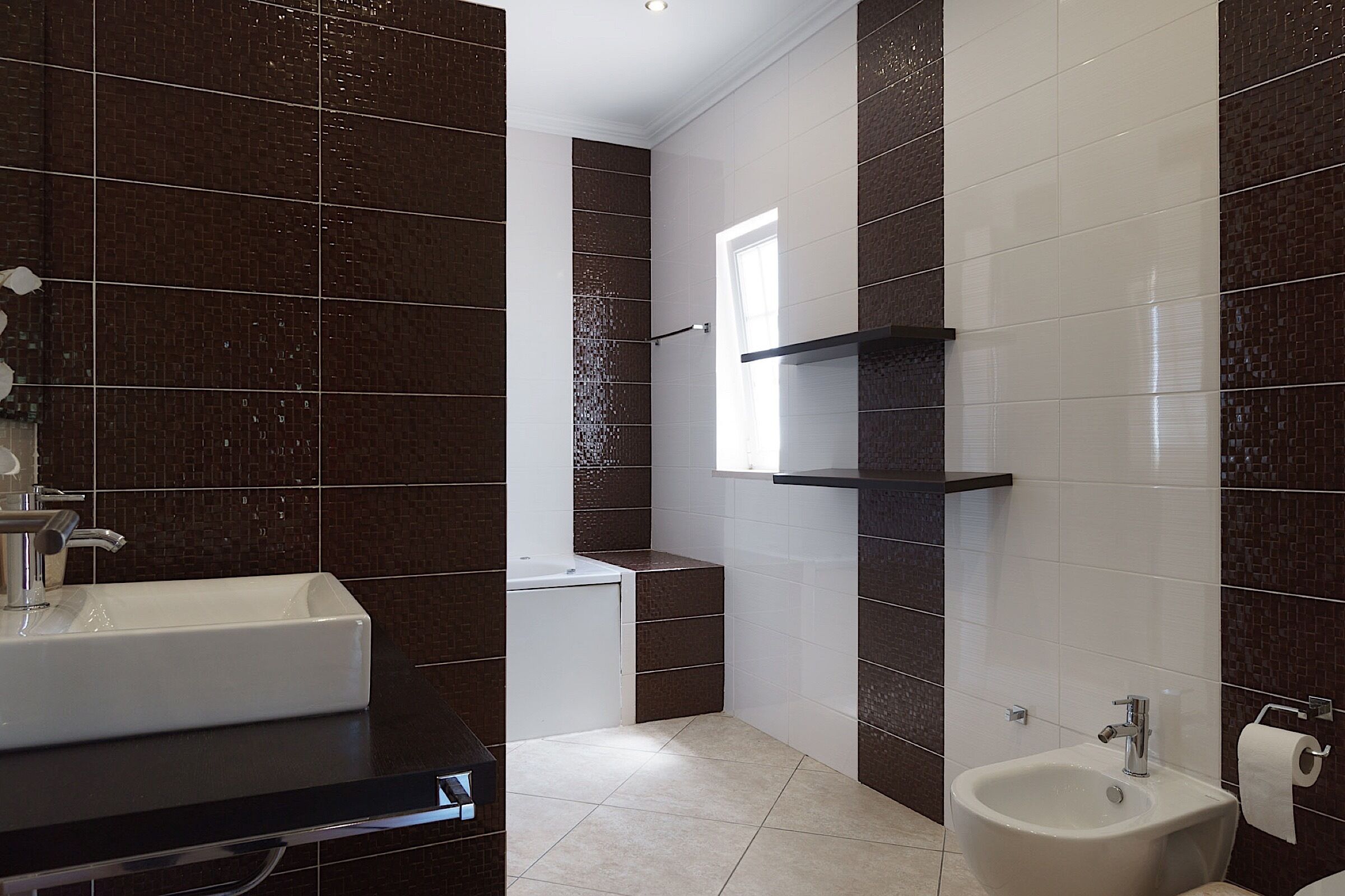 A modern bathroom with a large white sink, a bidet, and a toilet.