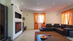 Ein modernes Wohnzimmer mit einer Eckcouch, einem flachbildfernseher an der Wand und einem Kamin.