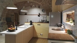 Una cocina con arco de piedra, vigas de madera, una isla central, un fregadero y un refrigerador.
