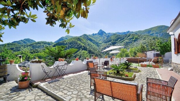 A patio with outdoor seating, potted plants, and a view of mountains. - Villa INN Costa Casa Ravello (Tramonti)