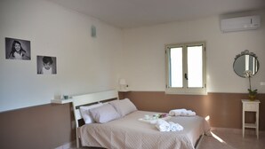 A neatly made bed with a tray of towels and a small table beside it. - Villa INN Costa Casa Ravello (Tramonti)