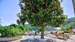 A patio area with stone flooring, outdoor seating, and a tree. - Villa INN Costa Casa Ravello (Tramonti)