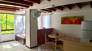 A small kitchen with a dining table, chairs, a refrigerator, and a window with curtains. - Apartamentos 3-54 (San Andrés)